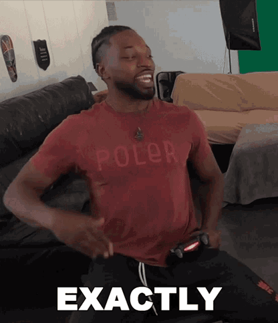 a man wearing a red shirt that says poler is sitting on a couch