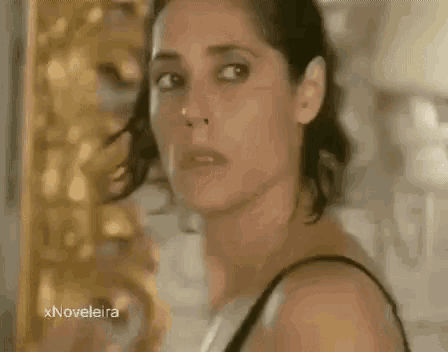 a woman in a black bra is looking at the camera with a sad look on her face .