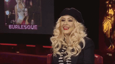 a woman is smiling in front of a burlesque poster