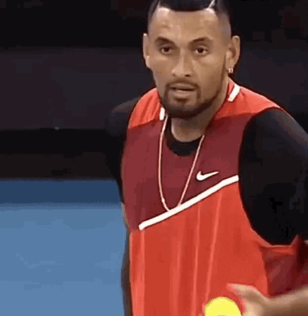 a man with a beard is holding a tennis ball in his hand .
