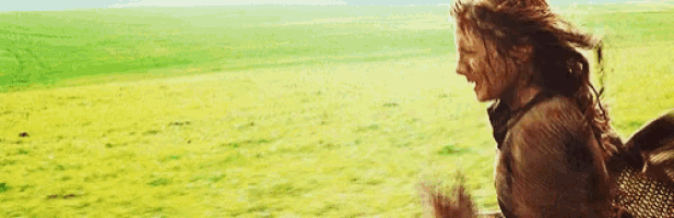 a woman is standing in a field of grass with her hands in the mud .