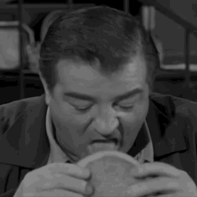 a man in a suit is eating a sandwich in a black and white photo