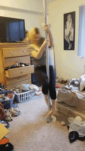 a woman stands on a pole in a bedroom with a picture of marilyn monroe on the wall