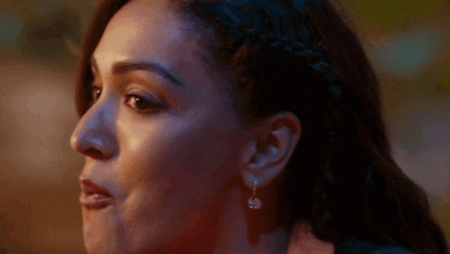 a close up of a woman 's face with a braid and earrings .