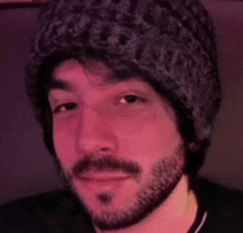 a man with a beard wearing a beanie and a black shirt .
