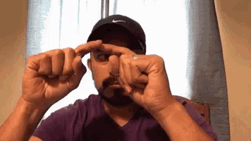 a man with a beard wearing a nike hat is making a funny face .