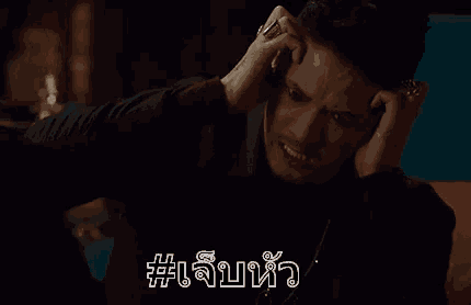 a man is talking on a cell phone in a dark room while holding his head .