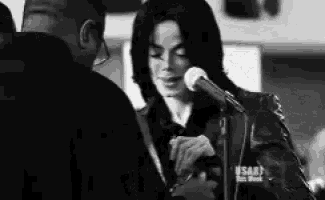 a black and white photo of a man talking to a man in front of a microphone that says usa on it