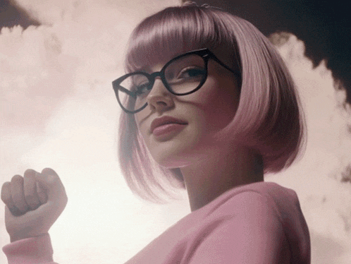 a woman with pink hair and glasses is wearing a pink shirt