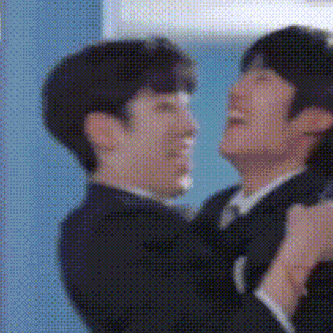 a couple of men in suits and ties are hugging each other in a room .