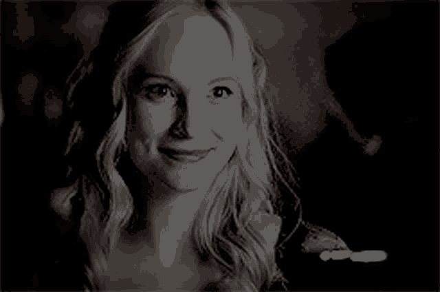a black and white photo of a woman with blonde hair smiling .