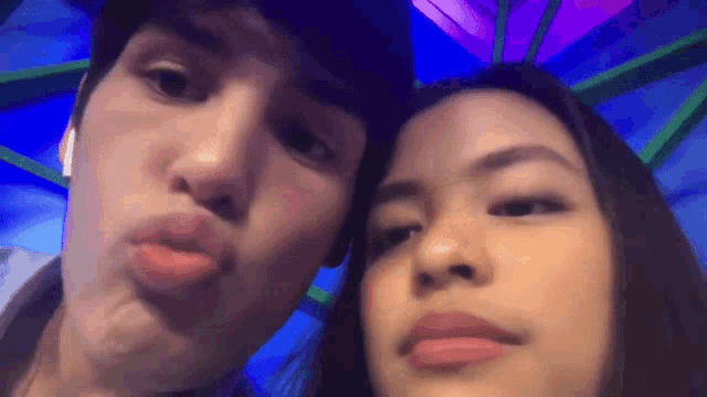 a man and a woman are posing for a picture with a purple background