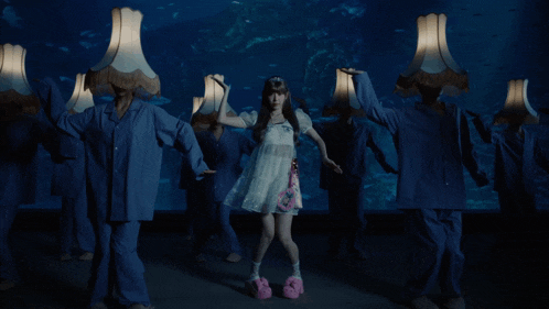 a girl in a white dress is surrounded by people in blue pajamas