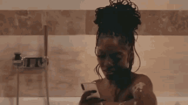 a woman is taking a bath while looking at her phone .