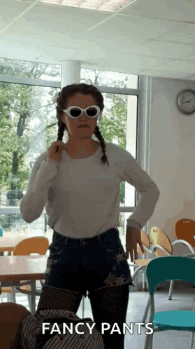 a woman wearing fancy pants and sunglasses is standing in a room