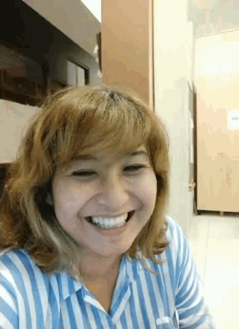 a woman in a blue and white striped shirt smiles for the camera
