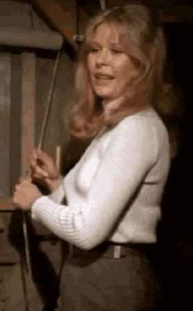 a woman is standing in a dark room holding a rope .