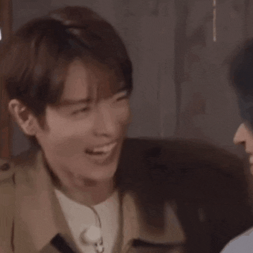 a close up of a man laughing and smiling while sitting next to another man .