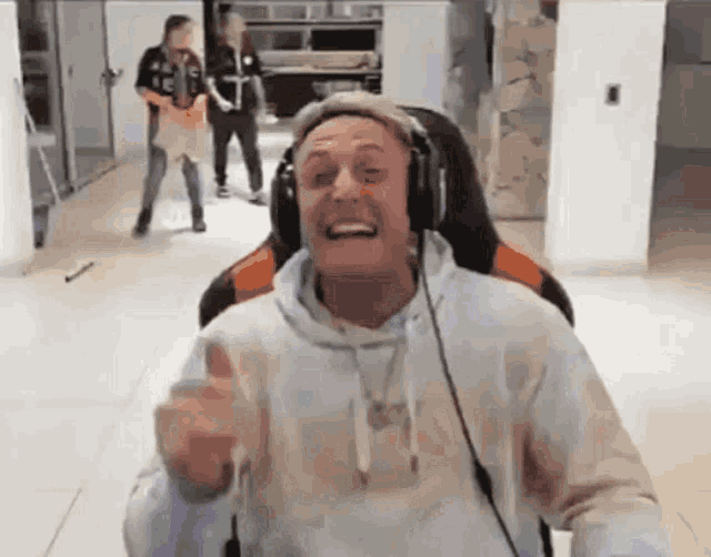 a man wearing headphones is sitting in a chair and giving a thumbs up .