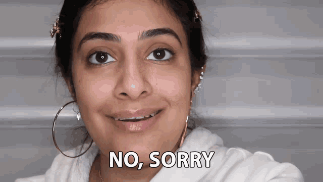 a woman says no sorry while smiling and wearing hoop earrings