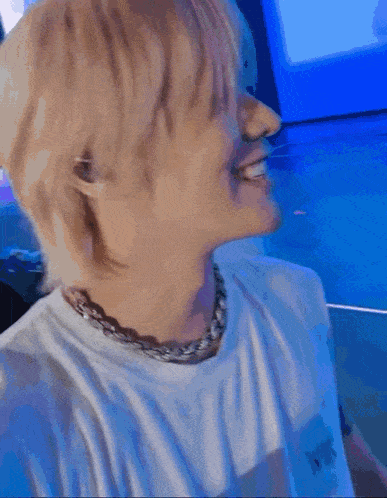 a close up of a person wearing a white shirt and a silver chain around their neck