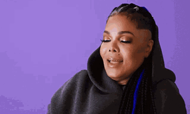 a woman with braids and a shaved head wearing a grey hoodie