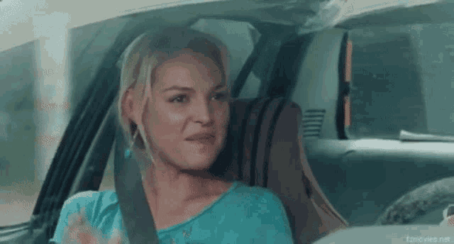 a woman is sitting in the back seat of a car talking to someone .