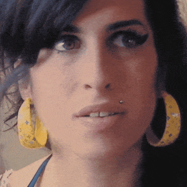 a woman wearing yellow hoop earrings has a piercing in her lip