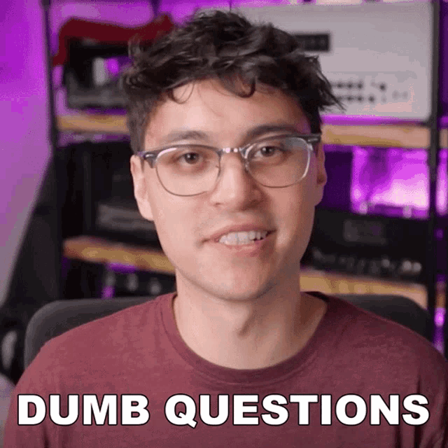 a man wearing glasses and a maroon shirt says " dumb questions " in white letters