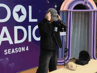 a man wearing a hat stands in front of a sign that says idol radio season 4