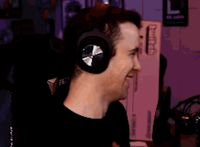 a man wearing headphones is smiling in front of a pink box that says twitch on it