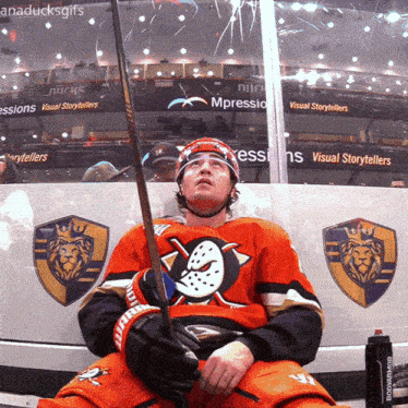 a hockey player is sitting in front of a wall that says visual storytellers on it