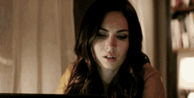 a woman is sitting in front of a laptop computer and looking at the screen .