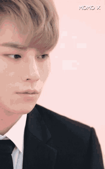a close up of a man 's face in a suit and tie against a pink background .
