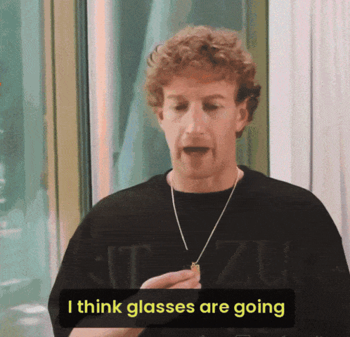 a man in a black shirt says i think glasses are going while holding a necklace