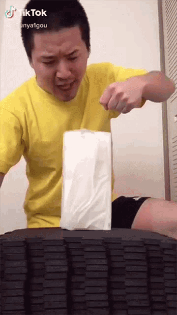 a man in a yellow shirt is holding a stack of tissues in front of a tire