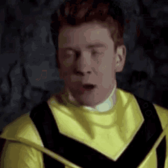a man in a yellow and black costume is making a funny face with his eyes closed .