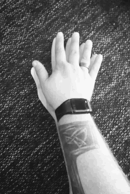 a black and white photo of a person 's wrist with a pentagram tattoo on it