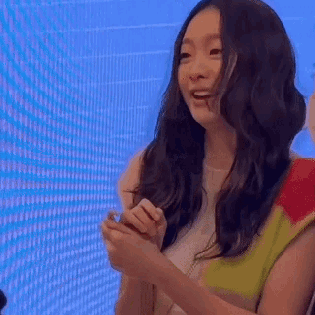 a woman with long hair is smiling and holding a blue object in her hands .