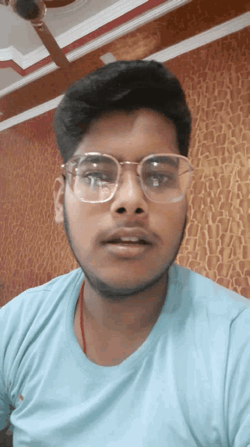 a man wearing glasses and a blue shirt looks at the camera