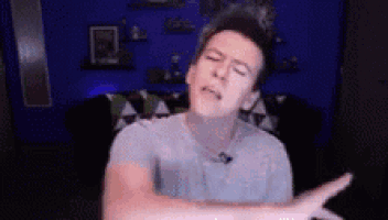 a man is making a funny face while sitting in front of a blue wall in a room .