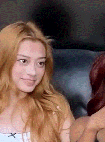a woman with blonde hair is sitting next to a woman with red hair on a couch .