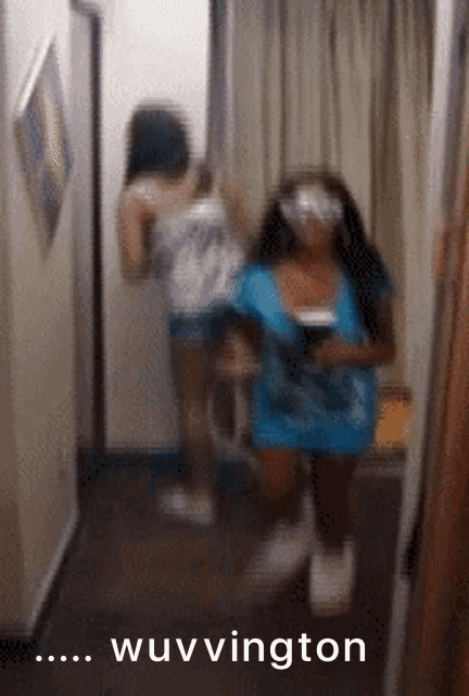 a blurry picture of two women in a hallway with the words wuvvington on the bottom right