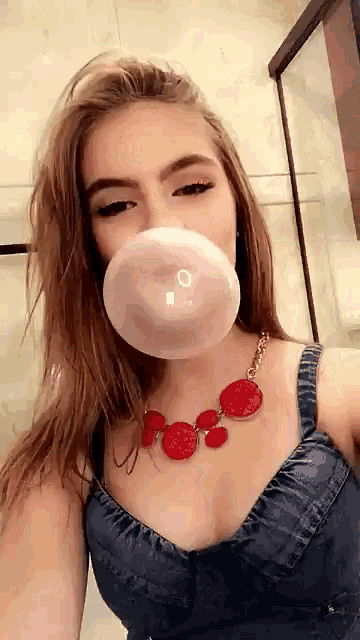 a woman blowing up a bubble with a red necklace