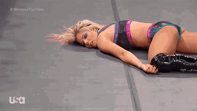a woman in a bikini is laying on the ground during a wrestling match .