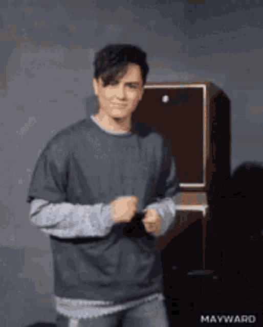 a man in a gray shirt is standing in front of a speaker ..