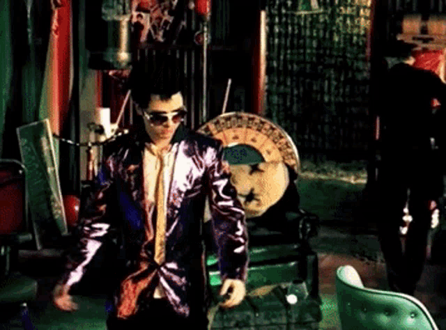 a man in a purple suit and tie is standing in front of a roulette wheel
