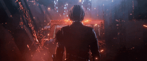 a man in a black suit is standing in front of a fire