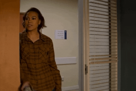 a woman in a plaid shirt is standing in a doorway in a hospital room .