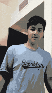a man wearing a blue brooklyn shirt stands in a room